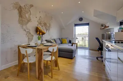 a kitchen and living room with a table and a couch at Stylish and Modern Flat with Free Parking - Pass the Keys in Cambridge