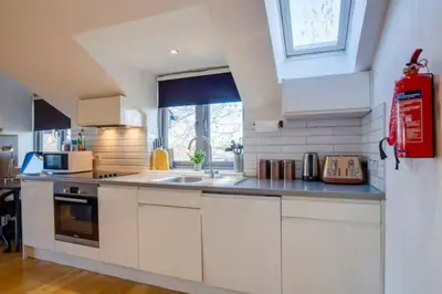 a kitchen with white cabinets and a red fire extinguisher at Stylish and Modern Flat with Free Parking - Pass the Keys in Cambridge