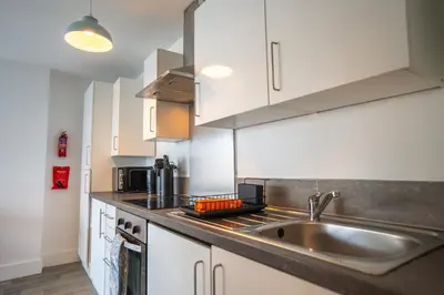a kitchen with white cabinets and a sink at Harlow Flat - Perfect for Families or Contractors in Harlow
