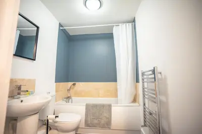 a bathroom with a sink and a toilet and a tub at Harlow Flat - Perfect for Families or Contractors in Harlow