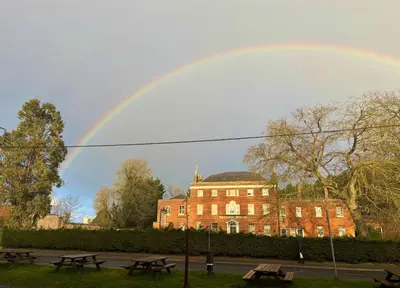 a rainbow over a building and picnic tables in a park at Brandon House in Brandon