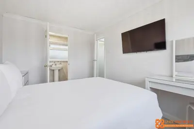a white bedroom with a bed and a flat screen tv at 4 Bed, 2 Bath Detached House, Parking, Fast Wifi in Colchester