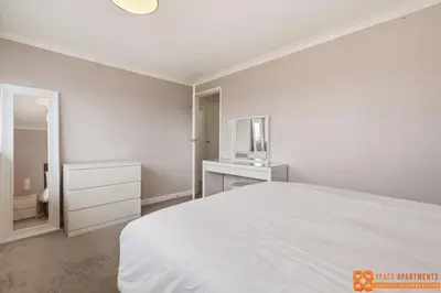 a white bedroom with a bed and a mirror at 4 Bed, 2 Bath Detached House, Parking, Fast Wifi in Colchester