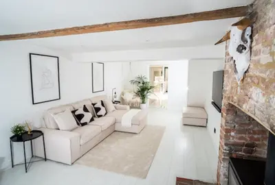 a living room with white furniture and a brick wall at Modern cottage! 5 mins from central line! in Theydon Bois