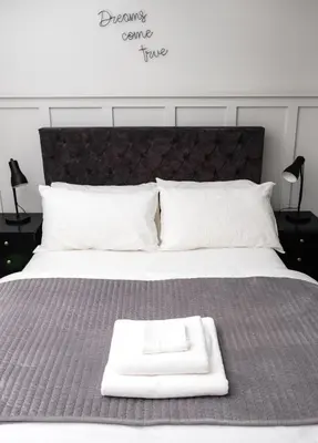 a bed with a white tray on top of it at Modern cottage! 5 mins from central line! in Theydon Bois