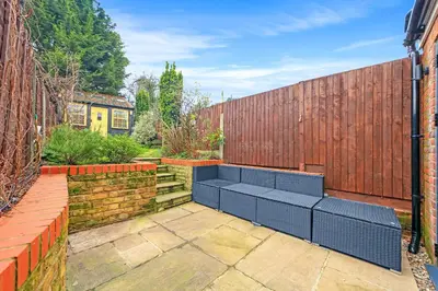 a garden with a bench in front of a fence at Modern cottage! 5 mins from central line! in Theydon Bois