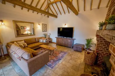 a living room with a couch and a tv at An elegant countryside hideaway with four indulgent ensuite bedrooms in Fressingfield