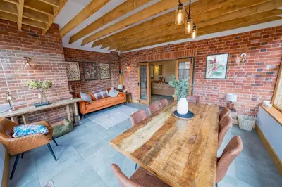 a living room with a wooden table and a brick wall at An elegant countryside hideaway with four indulgent ensuite bedrooms in Fressingfield