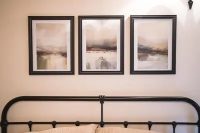 three framed pictures on a wall above a bed at An elegant countryside hideaway with four indulgent ensuite bedrooms in Fressingfield