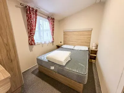 a small bedroom with a bed and a window at Seawick, 4 Bed, 10 Berth Caravan With Central Lounge, Dg & Ch Opal Rated in Clacton-on-Sea
