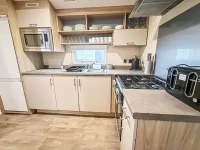 a kitchen with white cabinets and a stove top oven at Seawick, 4 Bed, 10 Berth Caravan With Central Lounge, Dg & Ch Opal Rated in Clacton-on-Sea