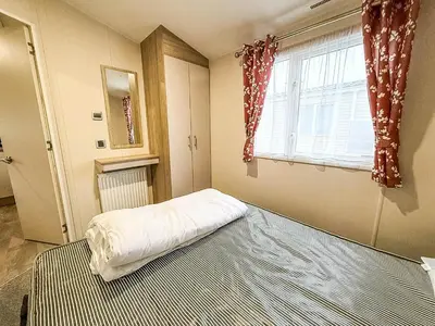 a bedroom with a bed and a window at Seawick, 4 Bed, 10 Berth Caravan With Central Lounge, Dg & Ch Opal Rated in Clacton-on-Sea