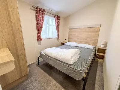 a small bedroom with a bed and a window at Seawick, 4 Bed, 10 Berth Caravan With Central Lounge, Dg & Ch Opal Rated in Clacton-on-Sea