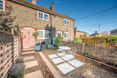 a brick house with a table and a pink door at Pink Cottage in Leiston