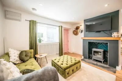 a living room with a couch and a fireplace at Pink Cottage in Leiston
