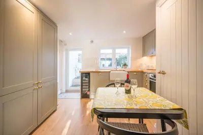 a kitchen with a table with two wine glasses on it at Pink Cottage in Leiston