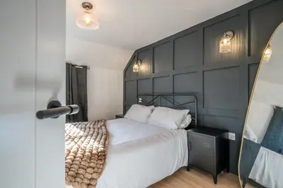 a bedroom with a bed and a black wall at Pink Cottage in Leiston