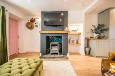a living room with a fireplace and a tv at Pink Cottage in Leiston