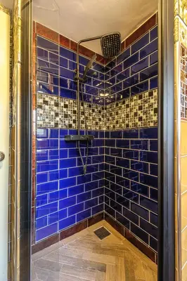 a blue tiled shower with a glass door at Luxury Rock & Roll Suite in Manor House in Saffron Walden
