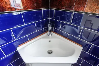 a bathroom with blue tiled walls and a sink at Luxury Rock & Roll Suite in Manor House in Saffron Walden