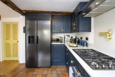 a kitchen with blue cabinets and a stainless steel refrigerator at Luxury Rock & Roll Suite in Manor House in Saffron Walden
