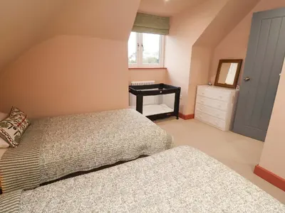 a bedroom with two beds and a desk with a mirror at 52 Lee Road in Aldeburgh