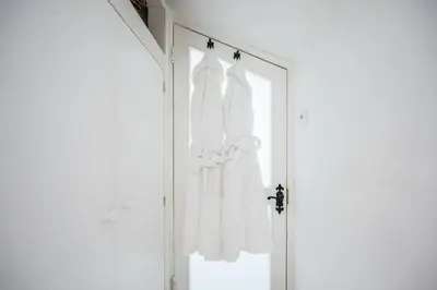 a door with two white dresses hanging on it at The Secret Cottage, Aldeburgh in Aldeburgh