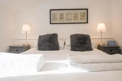 a bedroom with two lamps and a white bed at The Secret Cottage, Aldeburgh in Aldeburgh