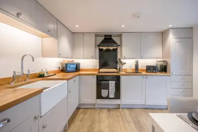 a kitchen with white cabinets and a sink at The Secret Cottage, Aldeburgh in Aldeburgh