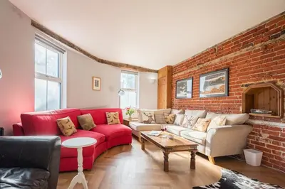 a living room with a red couch and a brick wall at The Knoll, Alderton in Alderton