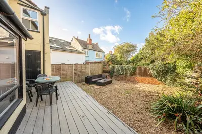 a backyard with a wooden deck with a table and chairs at The Knoll, Alderton in Alderton