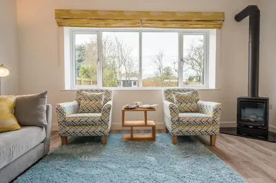 a living room with a couch and two chairs and a fireplace at 100 Leiston Road, Aldeburgh in Aldeburgh