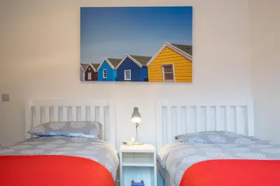 two beds in a room with a yellow and blue house at 100 Leiston Road, Aldeburgh in Aldeburgh