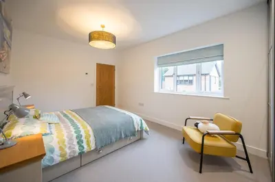 a bedroom with a bed and a chair and a window at 100 Leiston Road, Aldeburgh in Aldeburgh