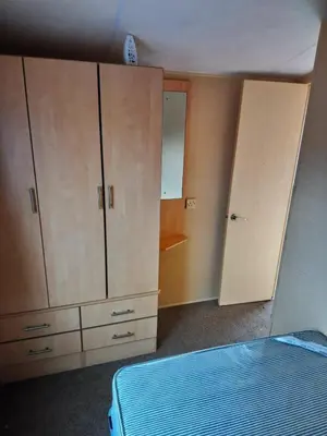 a bedroom with a bed and cabinets and a mirror at The Franklin in Saint Osyth