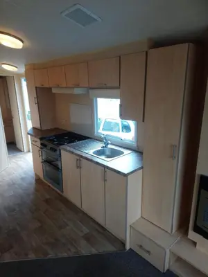 a kitchen with wooden cabinets and a sink and a window at The Franklin in Saint Osyth