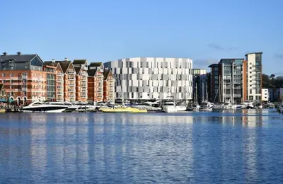 a city with buildings and boats in the water at Cozy Town Centre 2 Bed Apartment Close To Historic Landmarks And Great Restaurants in Ipswich