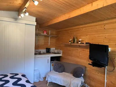 a living room with a couch and a tv on a wall at double bed short stay cabin in Martlesham