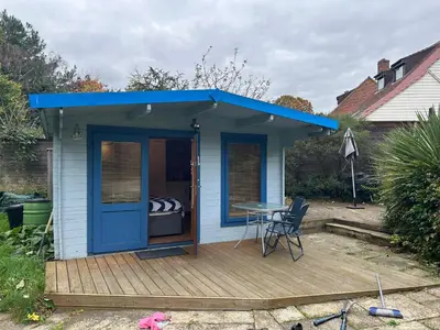 a blue shed with a table on a deck at double bed short stay cabin in Martlesham