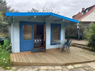 a blue shed with a table on a deck at double bed short stay cabin in Martlesham