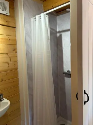a shower with a white shower curtain in a bathroom at double bed short stay cabin in Martlesham