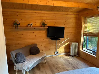 a living room with a couch and a tv on a wall at double bed short stay cabin in Martlesham