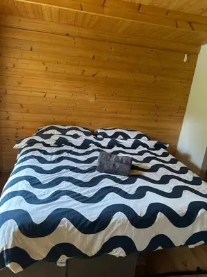 a bed with a blue and white blanket on it at double bed short stay cabin in Martlesham
