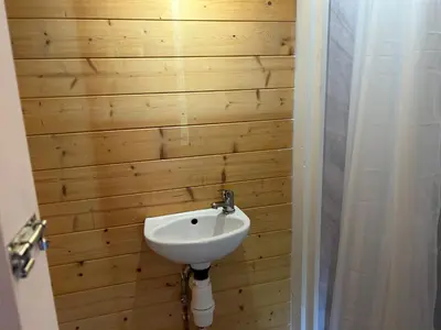 a bathroom with a sink and a wooden wall at double bed short stay cabin in Martlesham