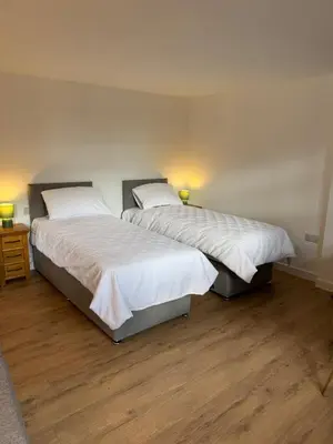 two twin beds in a room with wood floors at Poets View - Studio in Honington, Suffolk in Honington
