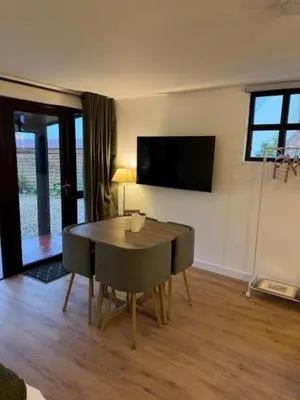 a dining room with a table and a tv on the wall at Poets View - Studio in Honington, Suffolk in Honington
