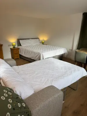 a room with two beds and a chair in it at Poets View - Studio in Honington, Suffolk in Honington
