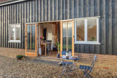 a house with glass doors and a table and chairs at 1 Bed in Orford oc-m34121 in Orford