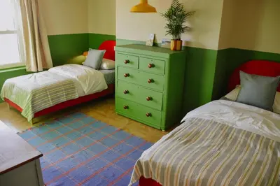 a bedroom with two beds and a dresser and a bed at Sunray House - Sea View, Beach Front Holiday Home in Felixstowe