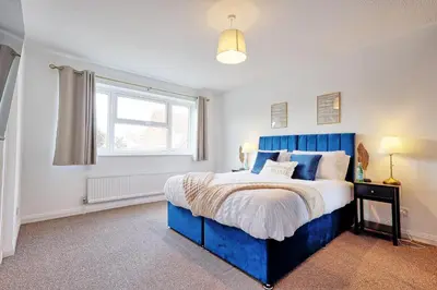 a bedroom with a blue bed and a window at Premium 5-Bed Home, Garden, Parking & High-Speed Wi-Fi in Nevendon